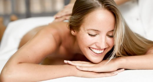 Young blonde woman having massage and smiling in the spa